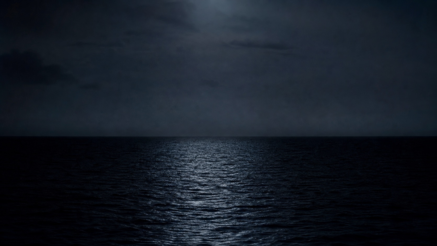 Dark open water beneath a quiet clouded night sky